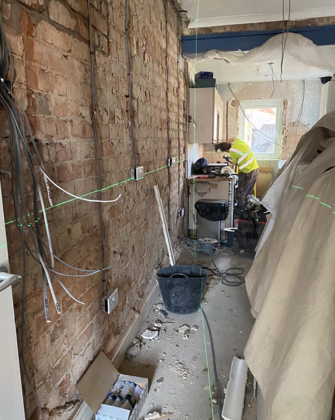 First fix rewire cables running down a stripped brick wall